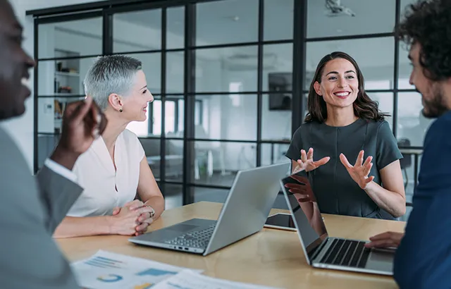 Lady smiling and giving a presentation at a group of people