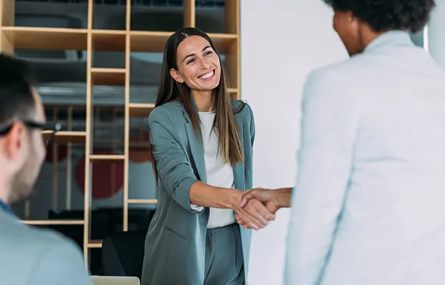 Lady associate smiling at another associate and shaking their hand